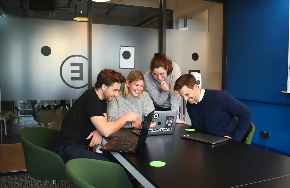 A team gathered around a laptop in a meeting room